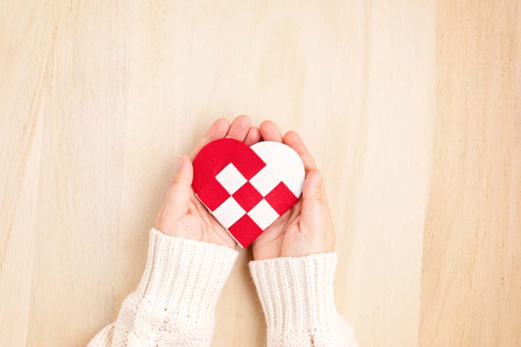 Giving Tuesday concept with woman hands holding red and white heart, charity day concept. Donation, philantropy, help and support idea. Top view, flat lay