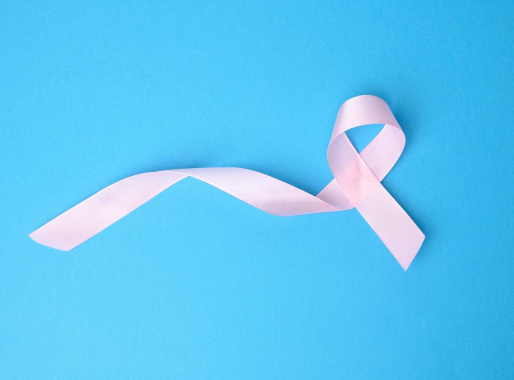 pink silk ribbon in the shape of a loop on a blue background. Symbol of breast cancer awareness