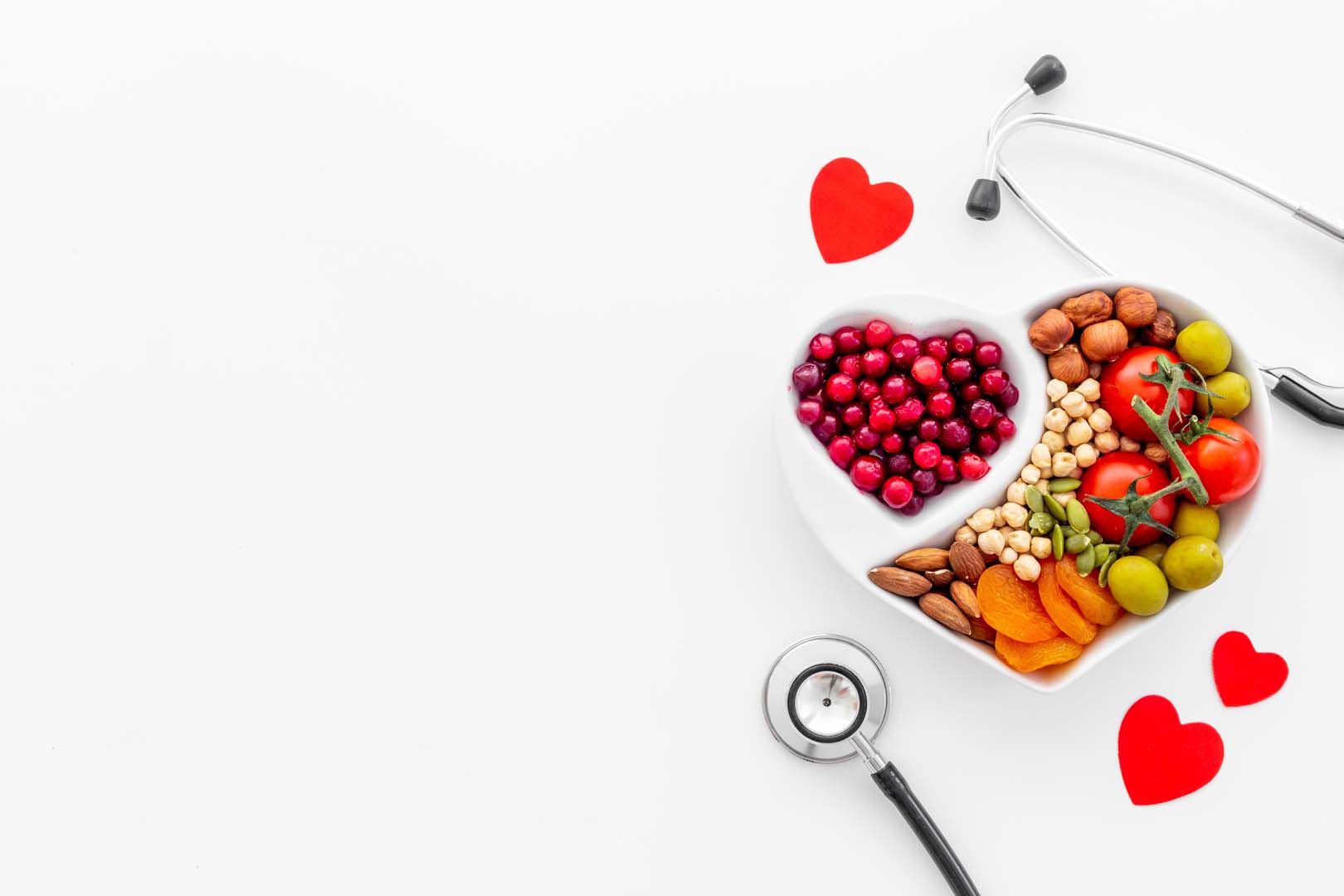 Cholesterol diet concept. Healthy food in heart shaped dish with stethoscope.