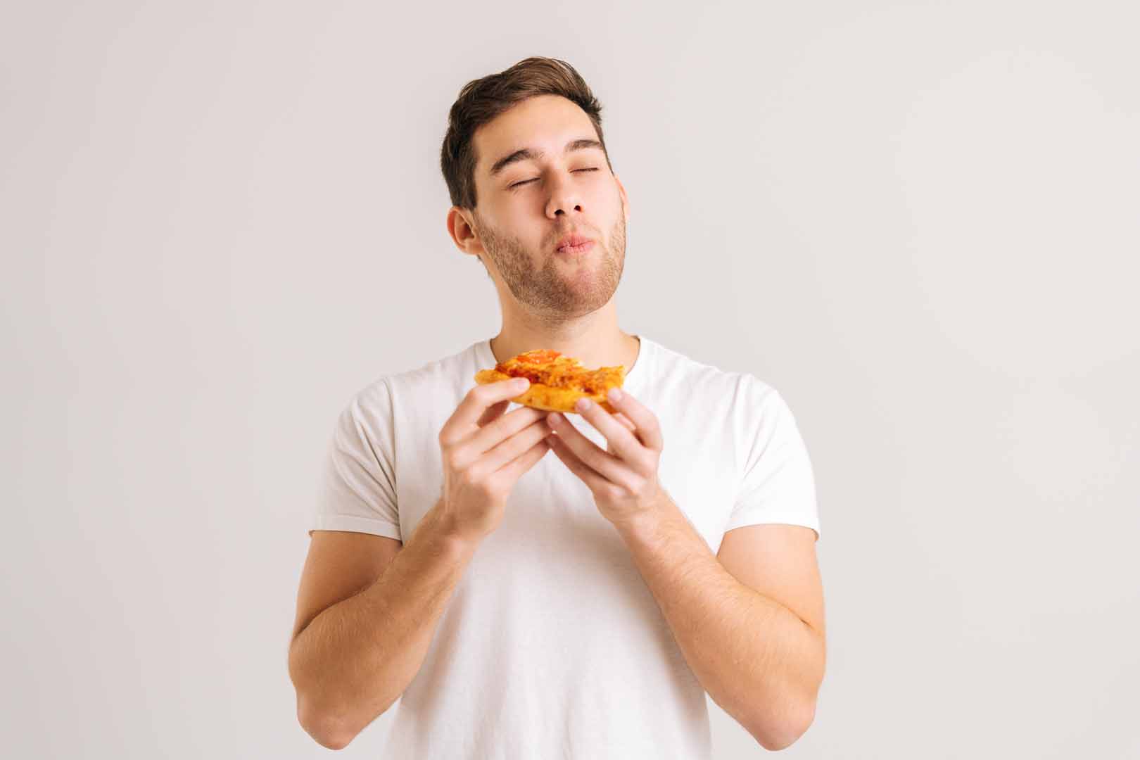 Portrait of handome young man with enjoying eating delicious slice of pizza